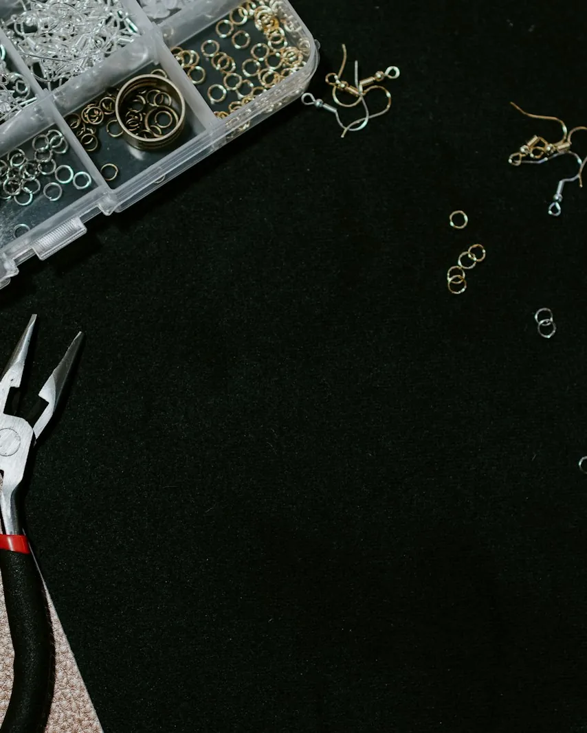 A jeweler's workbench with pliers, findings and a tray of components
