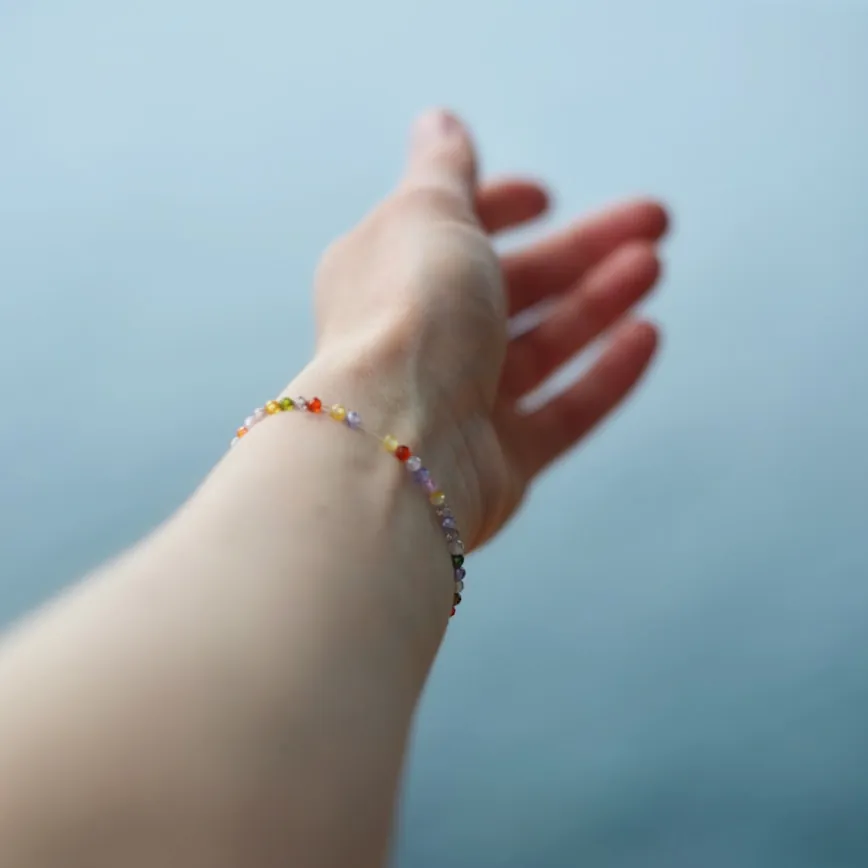 Bright beaded bracelet and ring worn on a hand against a contrasting backdrop