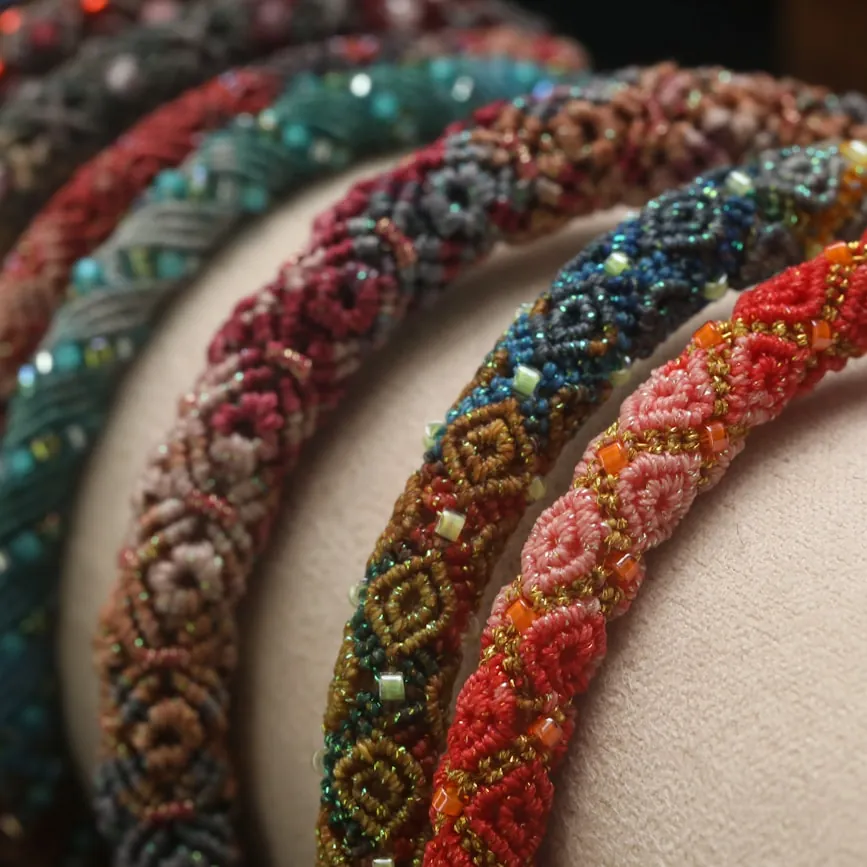 Beaded headbands in teal, berry and rust patterns lined up in a row