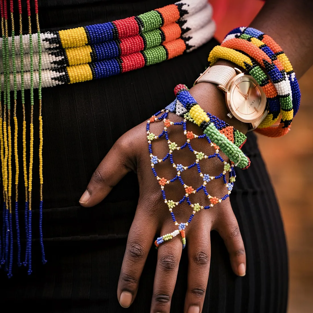 Hand holding a blue and yellow beaded statement necklace